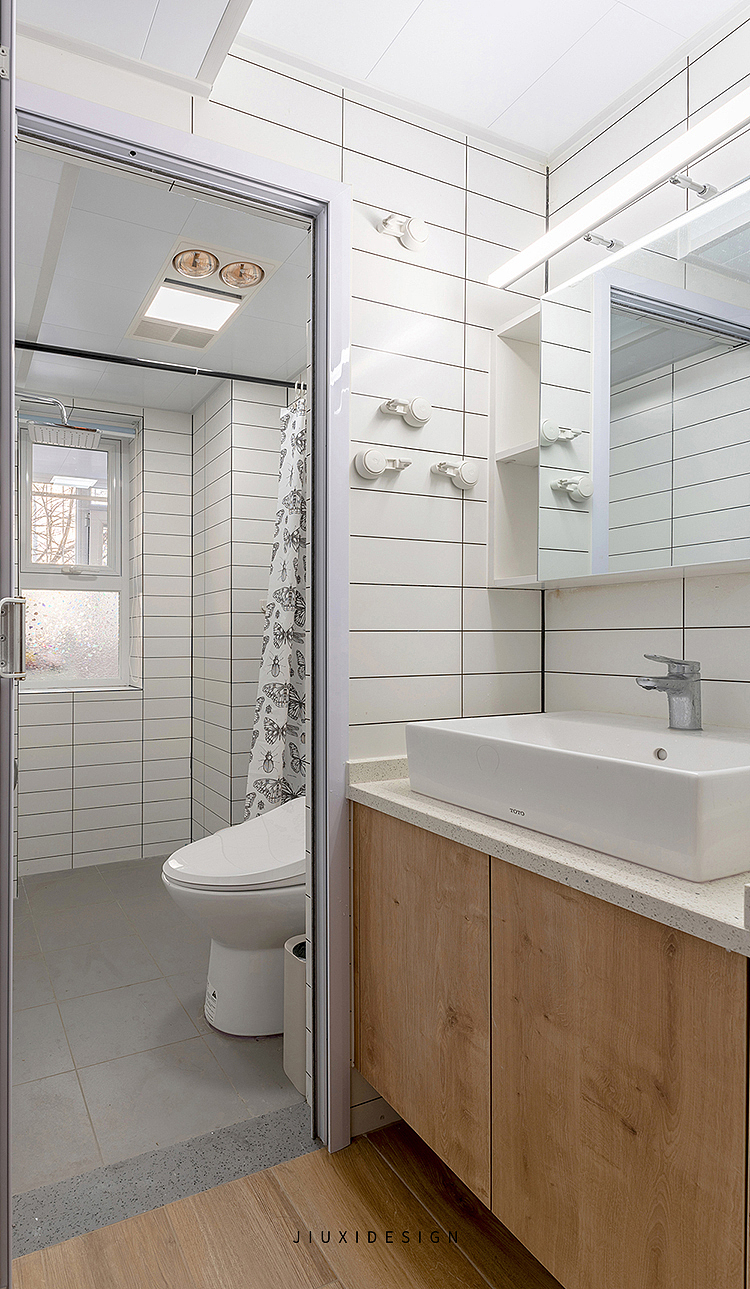 卫生间空间做了干湿分区，湿区内没有做淋浴屏的分割方式，而是采用了浴帘遮挡，方便照顾老人洗浴。卫生间内墙面采用的是小白砖，整体空间干净利落。
