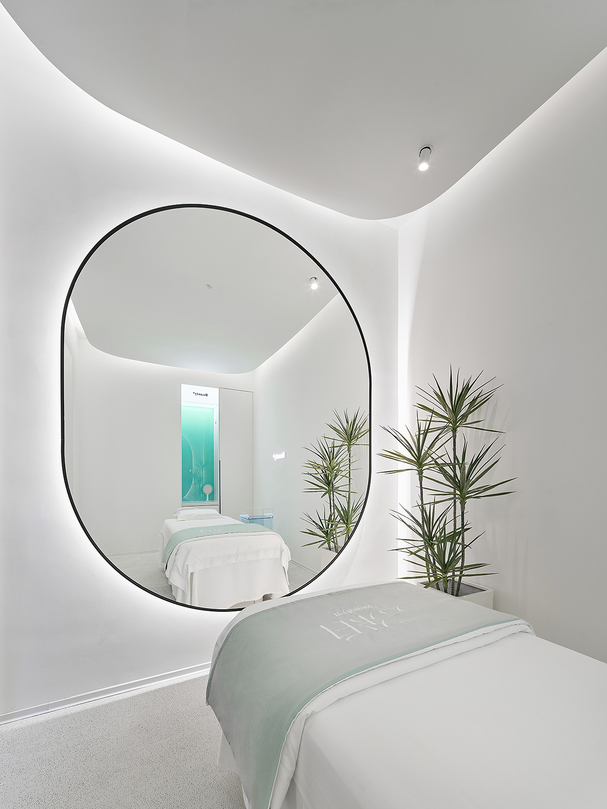 单人护理间格局呈矩形,顶部的弧形弱化空间棱角。纯净的空间点缀蓝绿色渐变玻璃立显清透,镜面从视觉上扩大空间。每个房间都配有香薰,并隐藏在衣柜内,只留一个释放香味的小孔。衣柜内部和小型梳妆台提供顾客所需的衣物存放、梳子皮筋等配套用品。