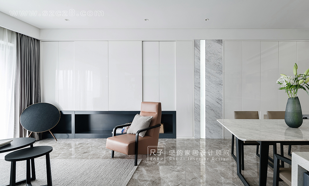 通过材质原有的肌理、质感及色彩，来丰富空间视觉的层次变化，橘色沙发起到点亮空间的作用。
白色的灯柱与大理石让整面墙的白色柜子不显单调，与另一头主卧的灯带相呼应，并以此来分割客餐空间。