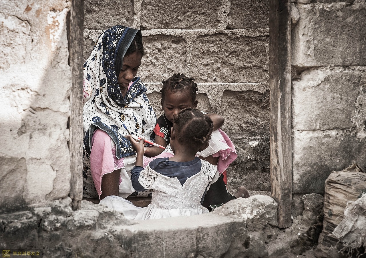 妇女抱着小孩,坐在门口看家护院。