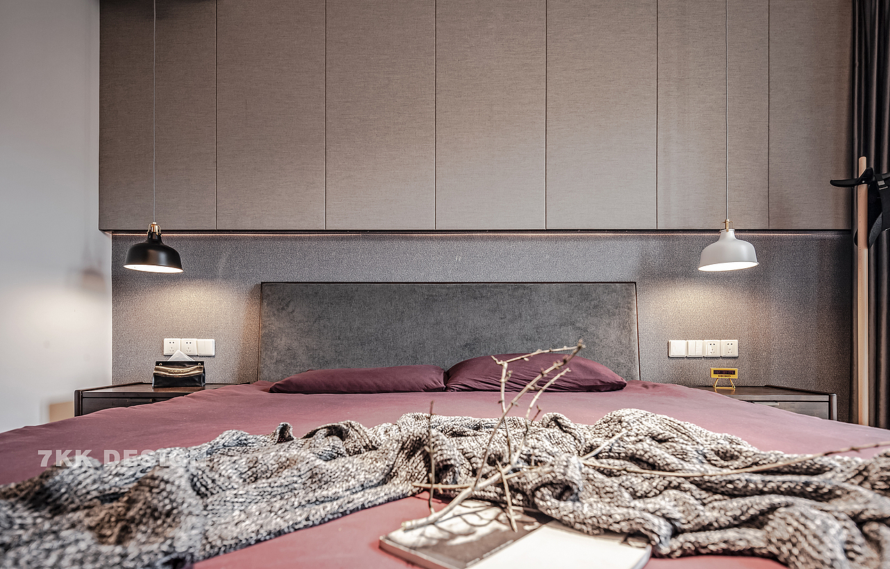 为拥有更多的储物功能，业主要求床头增加一排吊柜，隐藏式门板让空间更完整简洁。床头背景墙采用富有肌理的壁纸铺贴，左右黑白搭配的吊灯为空间带来不一样的时尚感。