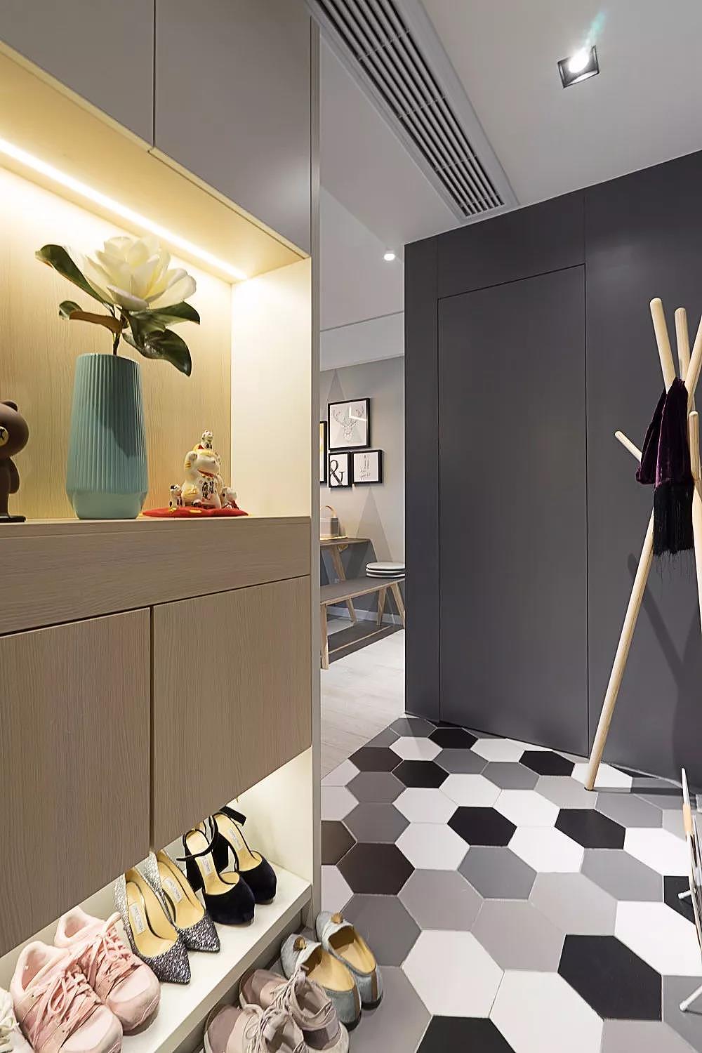 入户的玄关空间,一侧是做了嵌入式的到顶鞋柜,鞋柜的底部和中间都留空