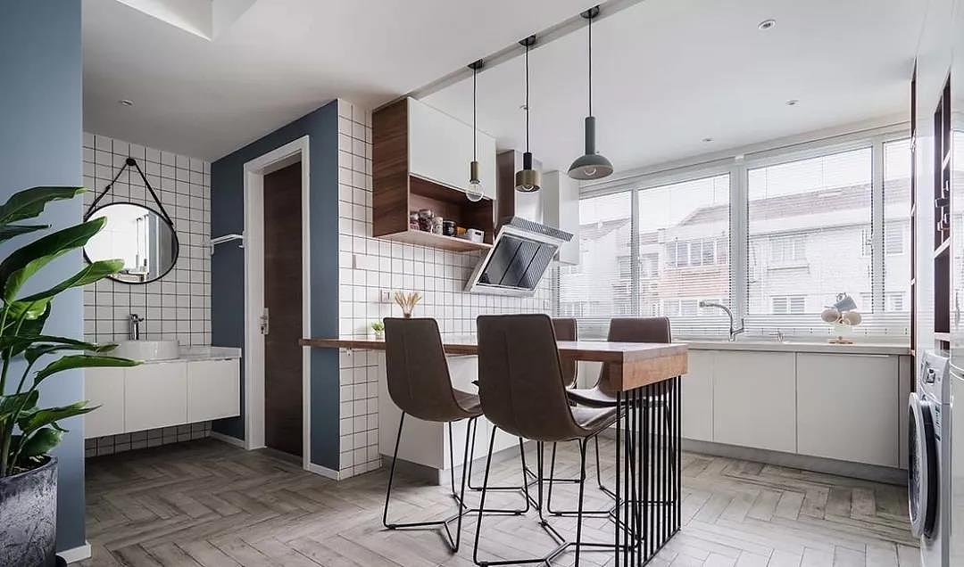 起居、盥洗、餐厅一气呵成,原木的餐桌与厨房台面连为一体,搭配别致的吊灯,营造了温馨的氛围。