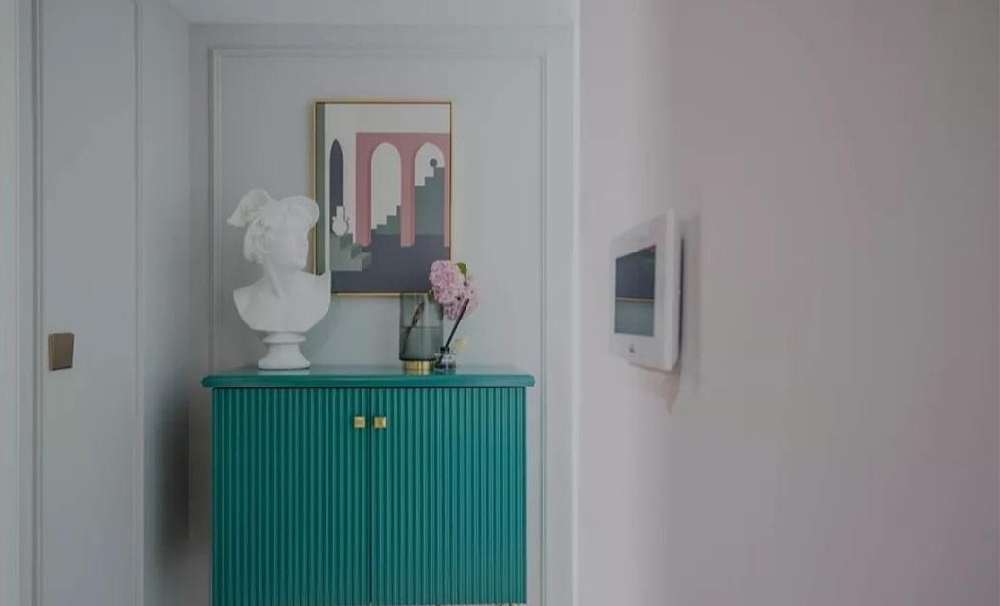 玄关是一个家的第一视觉印象区,特意选择了孔雀蓝柜子装饰,搭配白色雕塑摆件、粉紫色插花装置、金属装饰元素,奠定了整个空间精致轻奢的氛围。