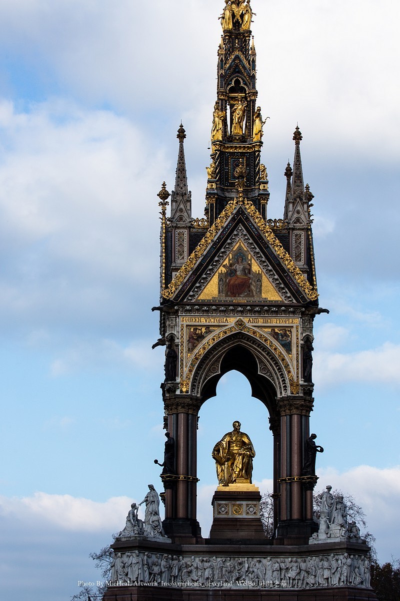 阿尔伯特纪念碑，顾名思义，维多利亚女王为了纪念1861年去世的丈夫阿尔伯特亲王而修建的一座拥有高54米的华丽天蓬，169位精美雕塑（包含浮雕人物）围绕的哥特复兴式亭廊纪念碑。耗资12万英镑（相当于现今的千万英镑吧- -+）工程消耗十年时间，由乔治吉尔伯特-斯科特爵士主持建造。恩，是真爱没错了0 0+有钱人的任性之举~不过也对，毕竟是国父的形象，该塑造也是无需质疑的~更何况在这尊纪念碑之前就有好多座纪念碑在英国各地被建起，看来皇室在民众心目中还是保持着非常高名誉的~。这尊黄金亲王坐像原本是由维多利亚女王最爱的雕塑家卡罗-马洛凯蒂男爵来完成的，然而第一版便被主持人否决~（有勇气啊朋友~）然而1867年在第二版完成前马洛凯蒂去世……1868年5月，转手由负责其中亚洲组群雕的约翰-亨利-福利完成这尊雕塑，12月素描模型获批，1870年全尺寸模型放置后得到了女王批准，1872年12月14日，纪念碑由女王亲自揭幕。1874年8月福利去世，而此时青铜铸造的人物已经完工，1875年底，对- -+在纪念堂已经揭幕3年后，镀金铜像隆重入座。也可谓是命途多舛了吧，两位雕塑家在制作这尊雕塑时去世……Emmmmmm= =+
