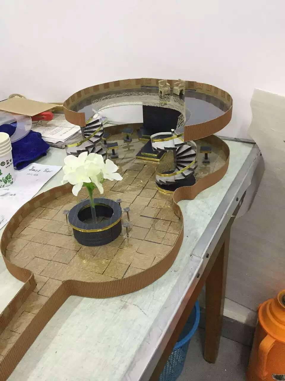 诺,二层架起来了,二层有一个亮点是用那个透明板做的,在二层中间走廊哪里的地板是透明的,可以看到下面的表演的,然后围栏扶手还是用那种有纹理的特种纸围起来,外围和一层是一样的用瓦楞纸。这里还做了一些那种小桌子,是人们可以围在一起一边品酒,一边欣赏表演的那种,设立在一层。