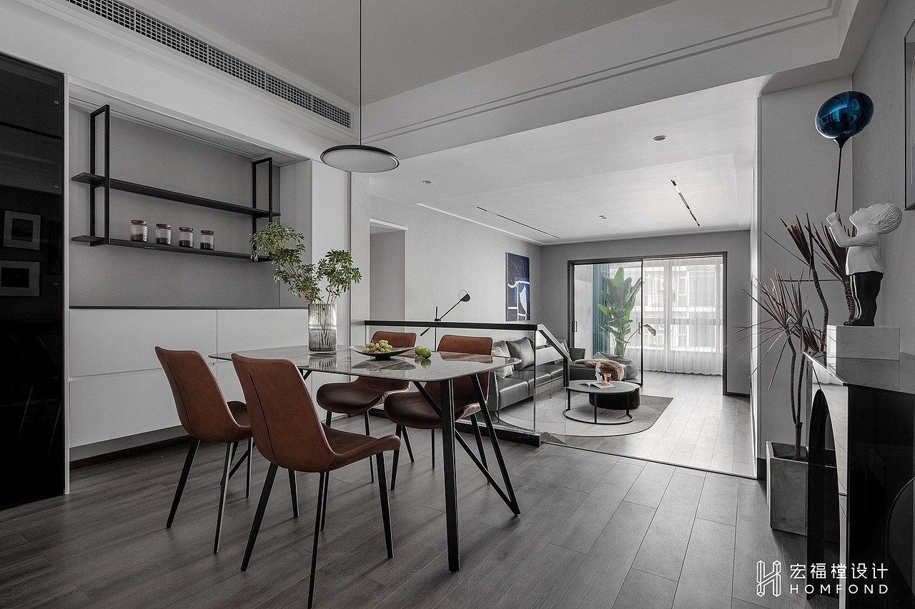 餐厅空间十分宽敞，位于正中的大理石餐桌散发出充满新鲜气息的氛围。左侧设计为黑玻展示柜、吊柜，以及与电视墙对称的白色储物柜。右侧摆放了亚克力材质的玄关桌，将硬朗的线条和柔美的拱券勾勒出空间景致。