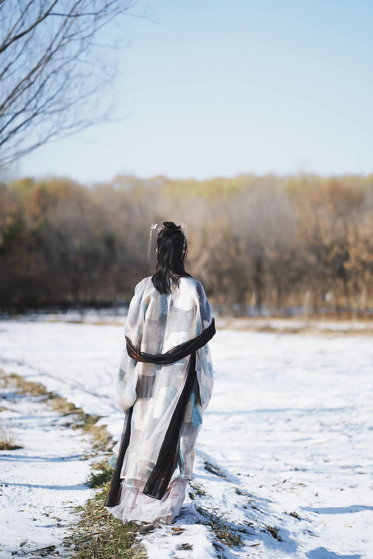 冬天，一个女孩在一棵毛绒绒的松树旁，穿着鲜艳的衣服。这孩子冬天会下雪照片摄影图片_ID:353925096-Veer图库