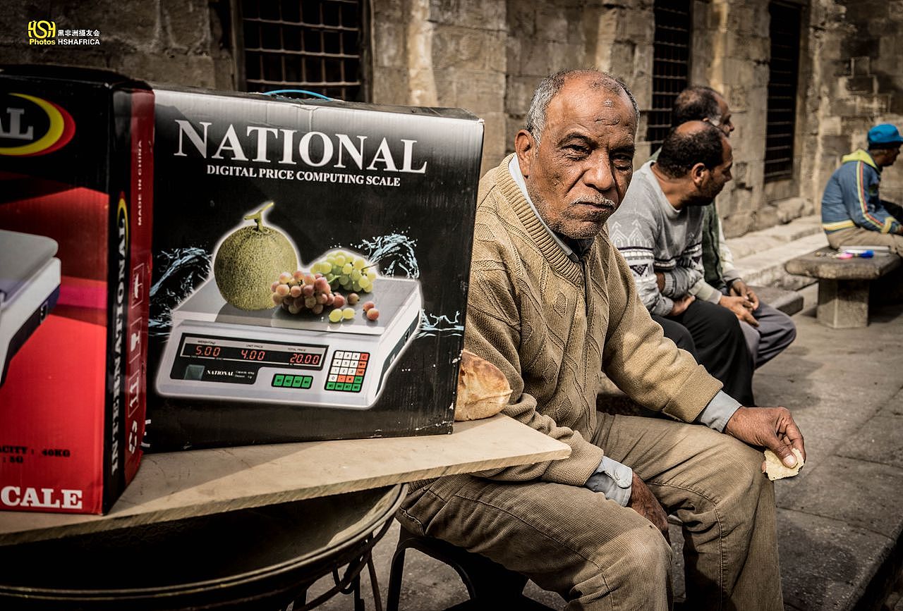 买电子秤的摊主，吃着刚才那个油煎饼。