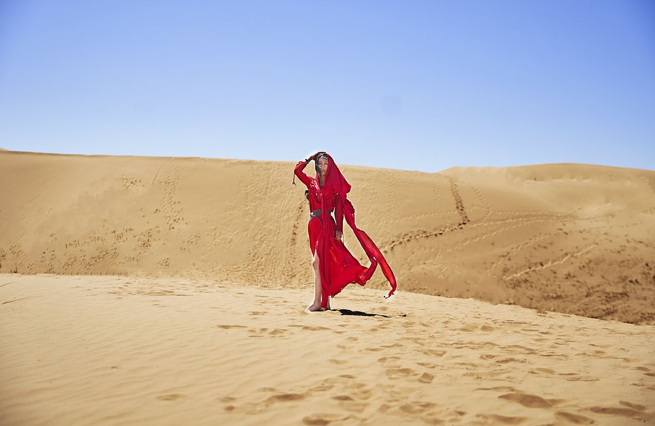 行走在沙漠中穿红衣的女子