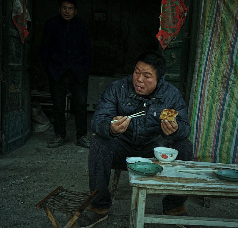 老头负责做馅饼,老太负责烧火翻烙,配合得及其默契.