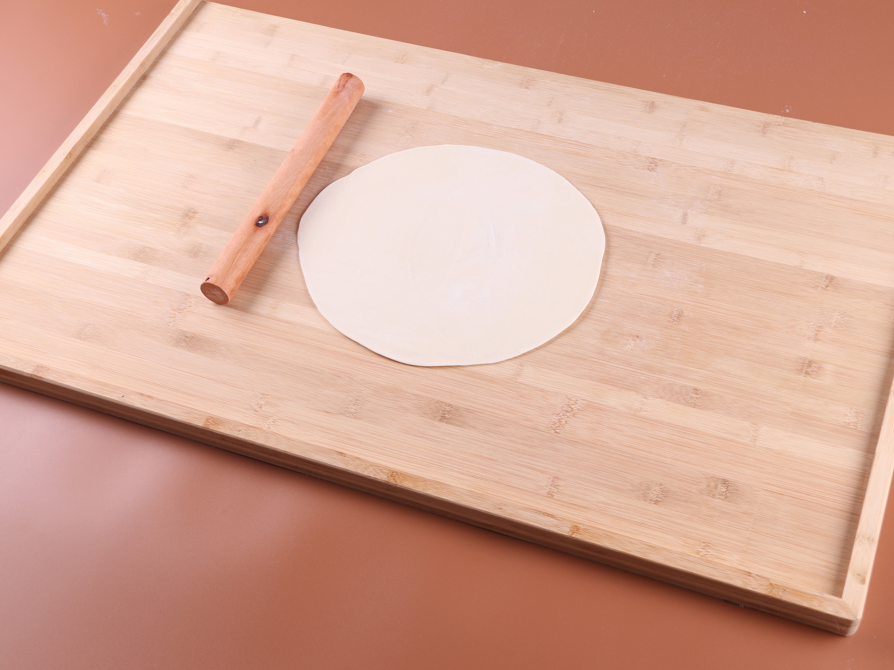 细节：厨师用擀面杖将面团擀在撒了面粉的木板上。高清摄影大图-千库网