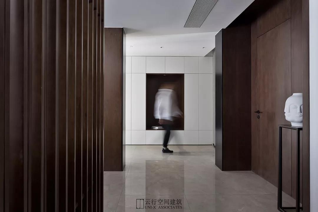 门厅 从入户的开始，便是利用自然光线的介入来转换入室的情绪感受，入厅转折后便是门厅和客厅过廊，藉由客厅沙发后的木制格栅过滤空间光线，在分隔客厅空间与入口走廊的同时，也维持了空间内通透与开敞的氛围，随影入画柔和引导空间的转换。