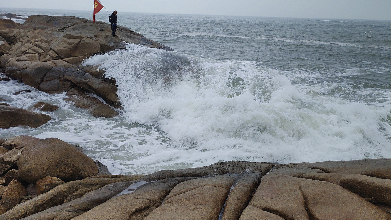 站在石头边 等海浪拍过来 就拍照。
