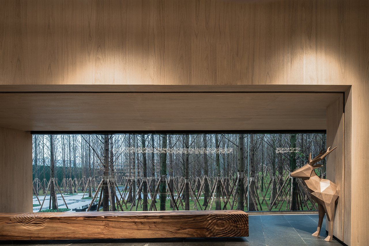 5000平米的水杉林是景观设计的大手笔,完美的将建筑「消隐」到自然里面。建筑设计以一面巨大的“镜子”面对这片水杉林,在“镜子”底部切割出一座小木屋。
<br>室内设计在此基调上,取纳自然所赋予的安静与宁性,将自然、空间和光影融为一体,塑造了一座当代又极富自然感的售楼空间,一个生长在森林中的会呼吸的小木屋。