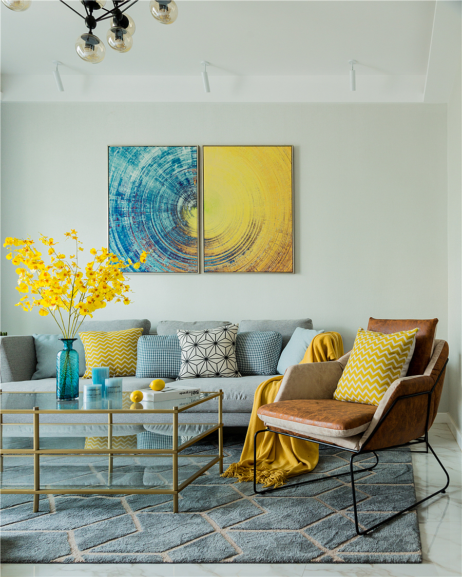 搭配跳色的黄色抱枕,个性的装饰画,金色的玻璃茶几,再配上几支亮黄色