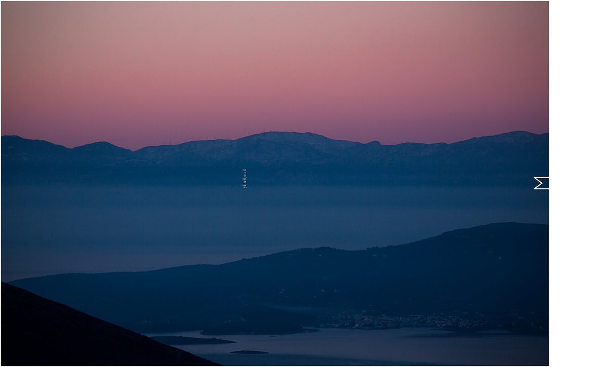 037:伴随着太阳的升起，远方还有些积雪的山顶渐渐透出了粉红色的天空，山后青色的阴影则积蓄着一些晨间的雾气。沿山脊而建的风力发电机缓缓的转动着，海边的小镇还沉浸在临晨十分的睡眼眯松。这幅景色之下，是古希腊传说中被认定为世界中心的“世界的肚脐”德尔菲。