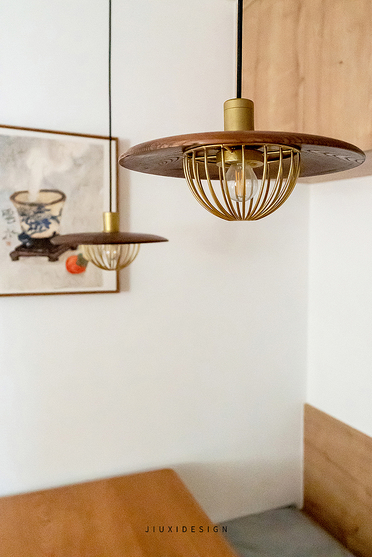 灯具是黑胡桃木飞碟造型吊灯，搭配古铜色的金属底托更显精致。
