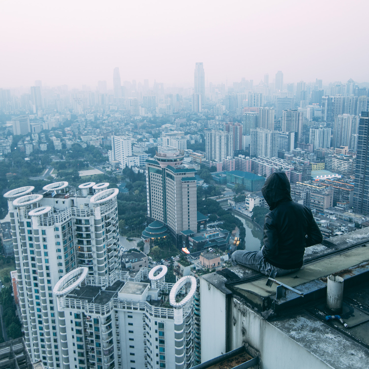 朦胧的城市中一个人站在楼顶俯瞰城市的喧嚣