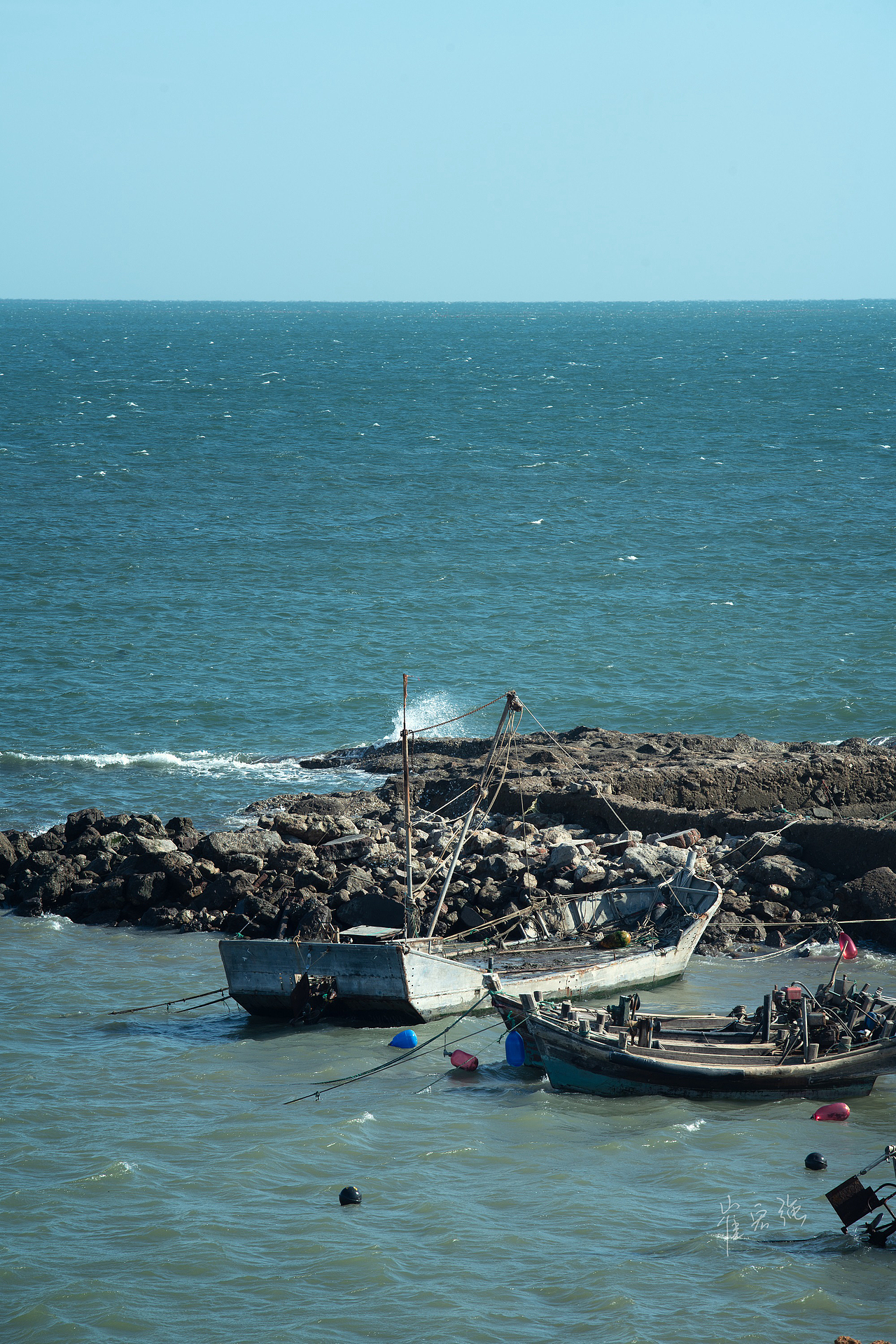 渔夫把船停在岸边,强烈的日光下,海浪拍打着渔船不停的晃动。