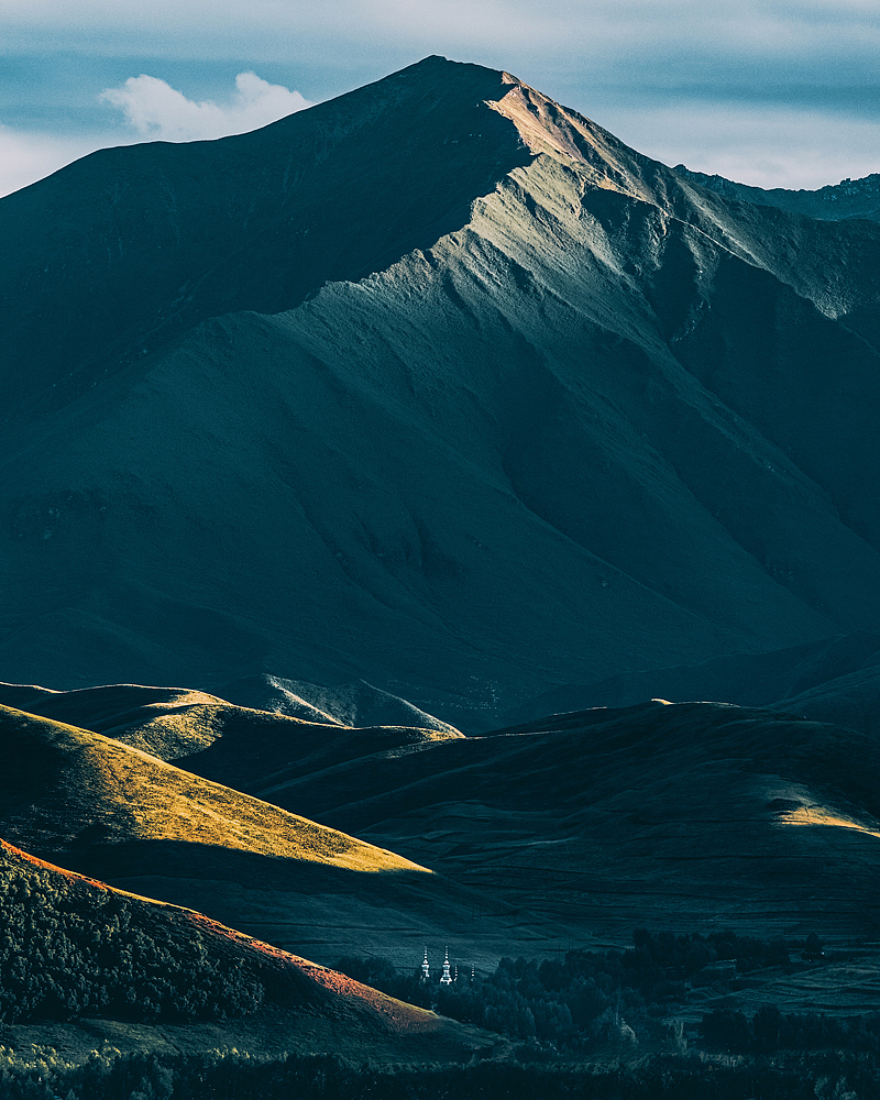 祁连草原上一处清真寺的建筑与远山遥遥相望。