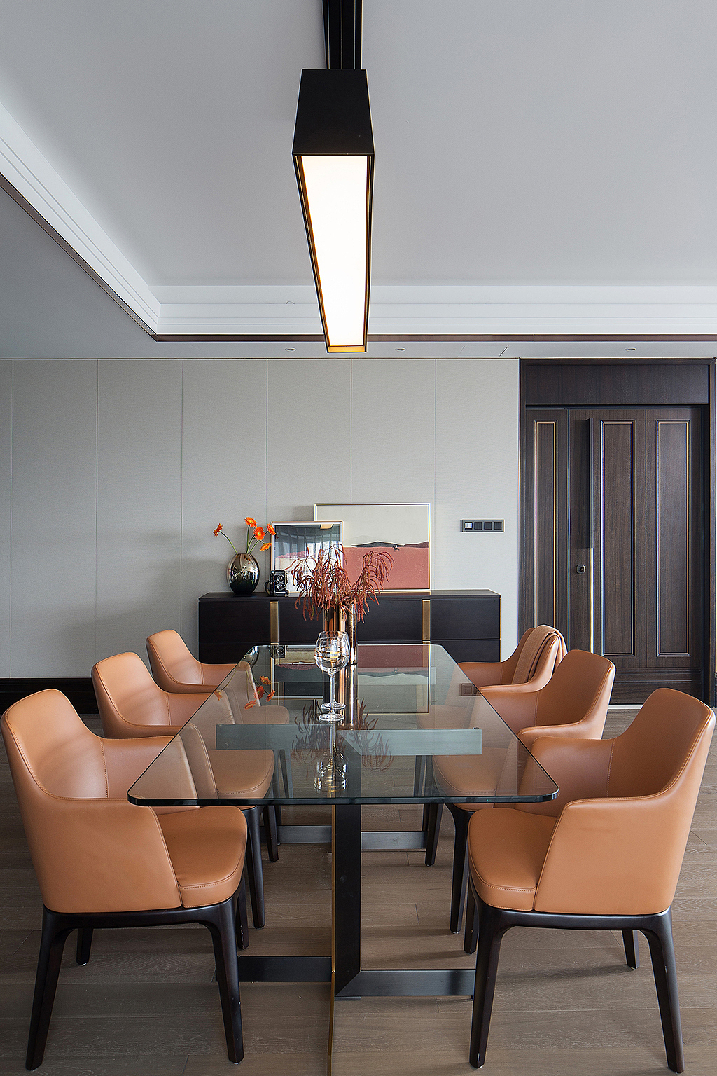 餐椅选定了脏橘色，既有橘色的热情，又蕴含灰度的高级内敛，搭配一盏线性灯具，开灯的瞬间温暖了整个空间。