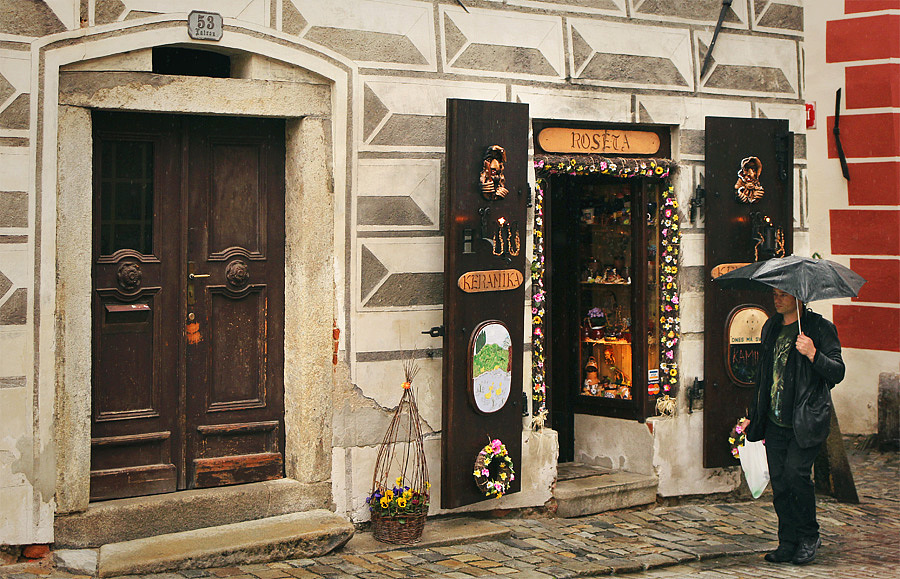 一名行人撑伞走过店铺。