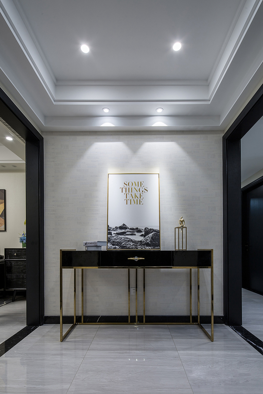 黑金的玄关柜，放上一幅金色金属边框挂画，加上假书及金色人物的摆放，显得简洁而富有层次感！
客厅