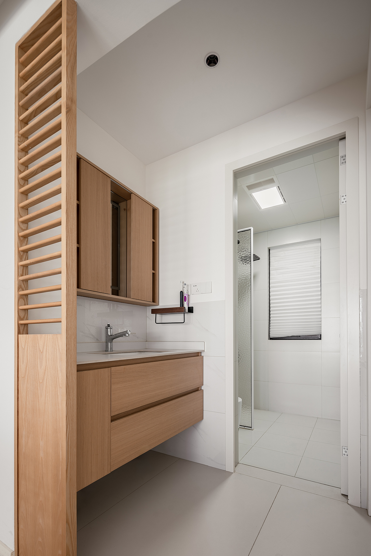 次卫生间干区采用的是胡桃木隔断,划分了空间尺度又有一定的遮挡装饰效果。和整体装修风格也契合。浴室柜采用的是原木和岩板的组合,清爽又自然,悬空的设计,方便打扫卫生,扫地机器人也可以轻松搞定。隐藏式镜柜避免了次卧开门见镜子。