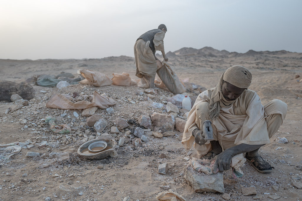 矿工们从地下敲下的金矿石拉上来后,由地上的淘金者负责把金矿石敲碎