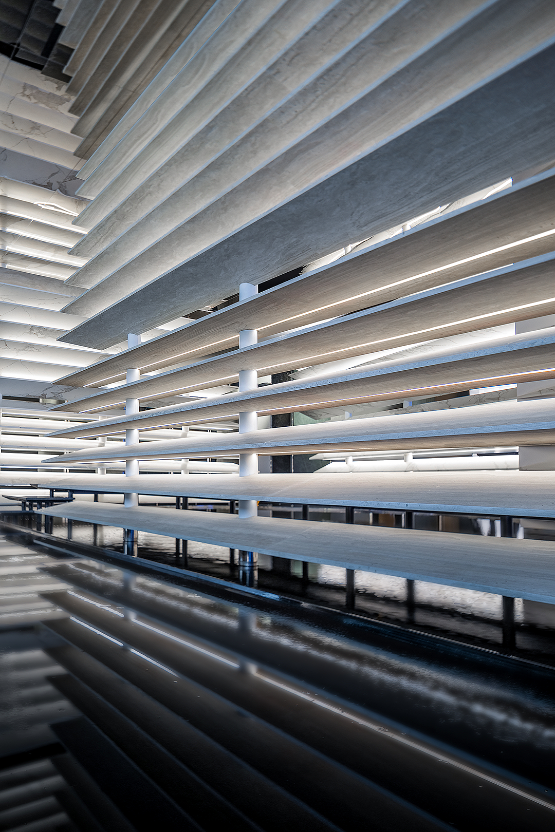 02开始与抵达
Departure and Arrival
这里,首先是一座美学生活馆。
墨色的建筑,在外围不规则形态的水景映射中静立,而令人驻足凝望的,是宽阔大窗中透露的一派写意:层层铺陈的平行线条是背景,灵动的水波纹路是点睛,再用一方长案代入主题。