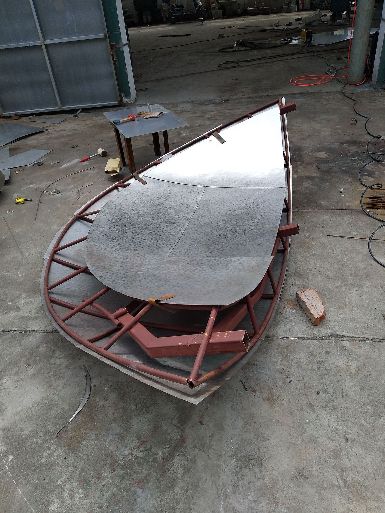 骨架放样完成之后进行不锈钢板的锻造,雕塑的锻造过程全部为纯手工锻造,雕塑师傅们用铁锤一锤一锤敲在不锈钢平面上,通过均匀的敲击排列使得不锈钢板变得有弧度。这个过程说起来很容易,但是实际操作的时候难度系数是非常高的,需要师傅们凭着经验去敲击,然后多次的放在雕塑骨架上对照,以确保造型的准确,一般一个合格的雕塑锻造师傅至少从业5年以上。并且锻造过程会产生巨大的噪音,长期对锻造师傅的身体多少还是有影响的,不锈钢板的硬度也是很高的,敲击的时候还会产生很大的震动通过手臂传至全身,所以这些锻造师傅们牺牲还是蛮大的,所以他们的工资也是雕塑行业里比较高的。