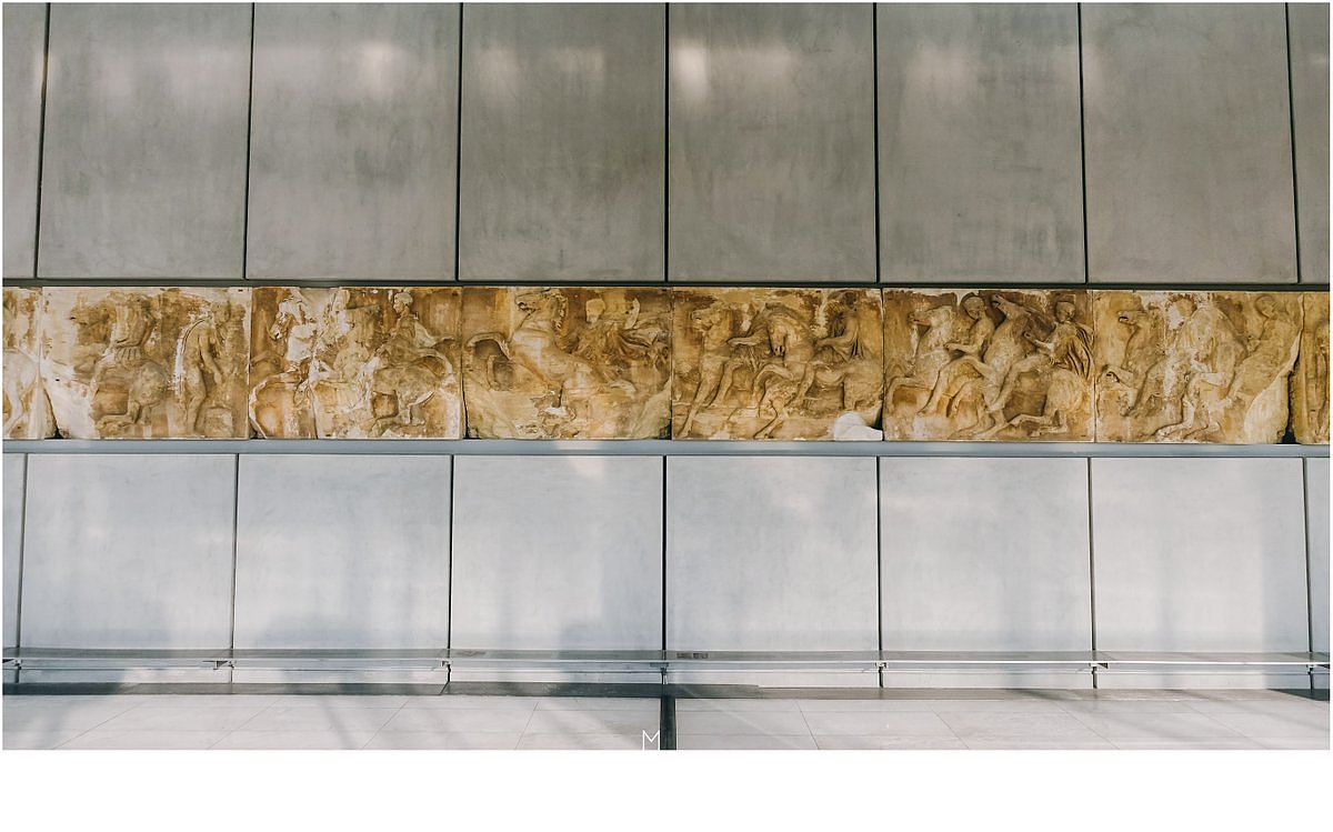 031:卫城博物馆的首层展览着一些当地发掘出的古希腊文物，地下则透过透明的玻璃可以看到原址之下的Makrygianni遗迹考古现场，二层是一些雕塑作品的展示，二层半的位置在中心突出了一个区域，展放的便是之前所提到的女神柱。三层的位置，根据帕提农的方向走势，大小角度，布局安排，还原了一个真实的帕提农神庙空间平面。这部分大概是设计者最为用心的地方，周围是仿制的帕提农神庙浮雕，他们用纯白色来提示着这部分是被窃走的部分，用空缺来告诉我们这里的这部分已经遗失或损毁，原品也有少数保留其中，让人不胜唏嘘这座神庙的经历。漫步其中，努力回忆着在大英博物馆中看到的那些神乎其技的浮雕和雕塑，五味具杂。文物的问题总是国家之间的权衡，物归原主也有时并不是轻而易举的事情，大英的设施和安全度称得上顶级，而希腊之前因奥运与这些博物馆设施的扩建导致的经济崩溃也历历在目，所谓保护，真的不知应该如何来界定他们。
