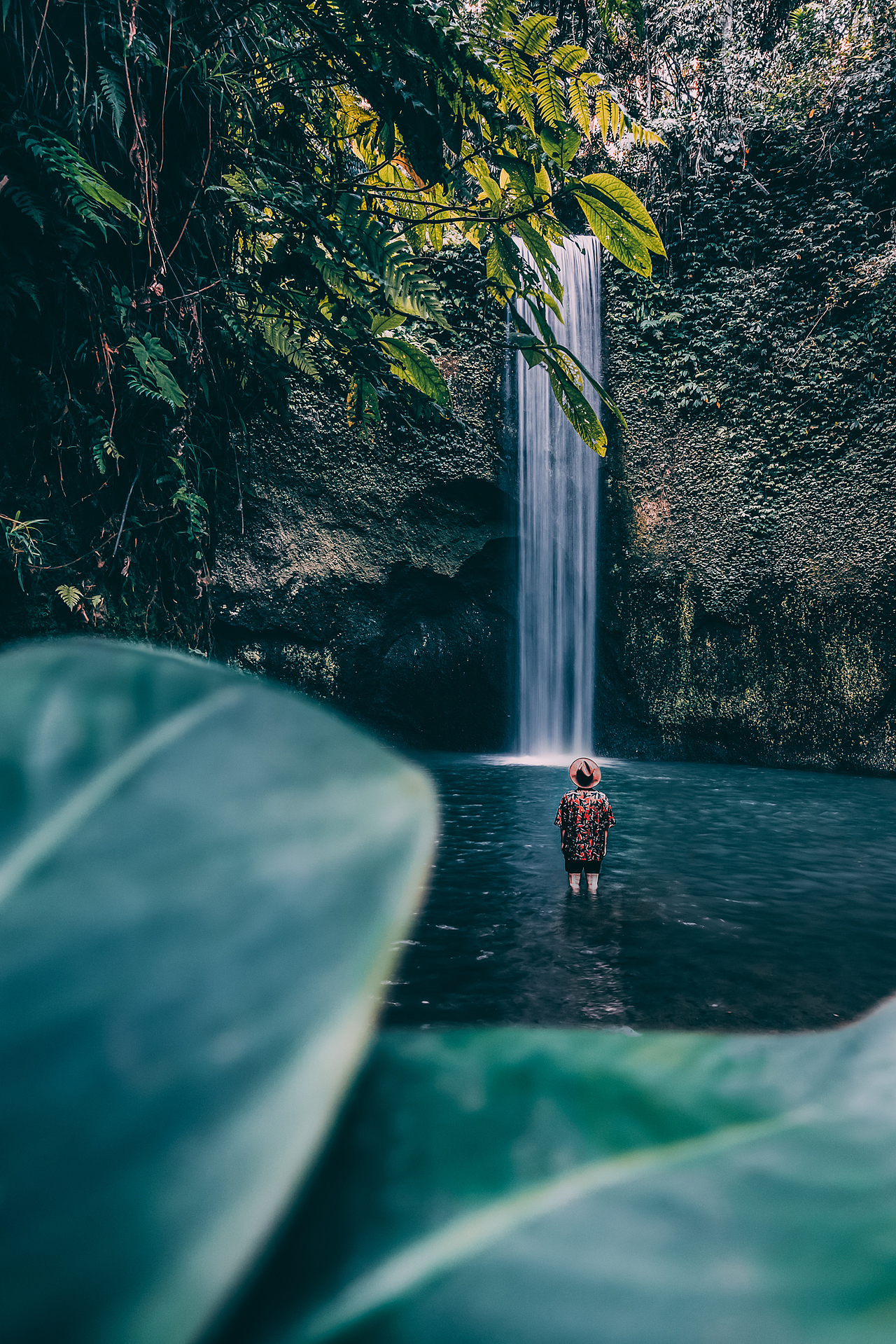 【旅行中该有的样子】
这张照片也是2019年自己比较喜欢的照片之一，拍摄于巴厘岛的Tibumana瀑布。这张照片其实就是有提前策划的照片，因为其实瀑布本身并不大，并且现场环境很杂乱，我就在四处找来叶子当做画面的前景。不过拍摄中同样也会遇到很大的挑战，因为相机可以放在三脚架上不动，但是手拿着的叶子就很难固定住拍出想要的画面，最后按了200多次快门，才拍下这张比较满意的作品。