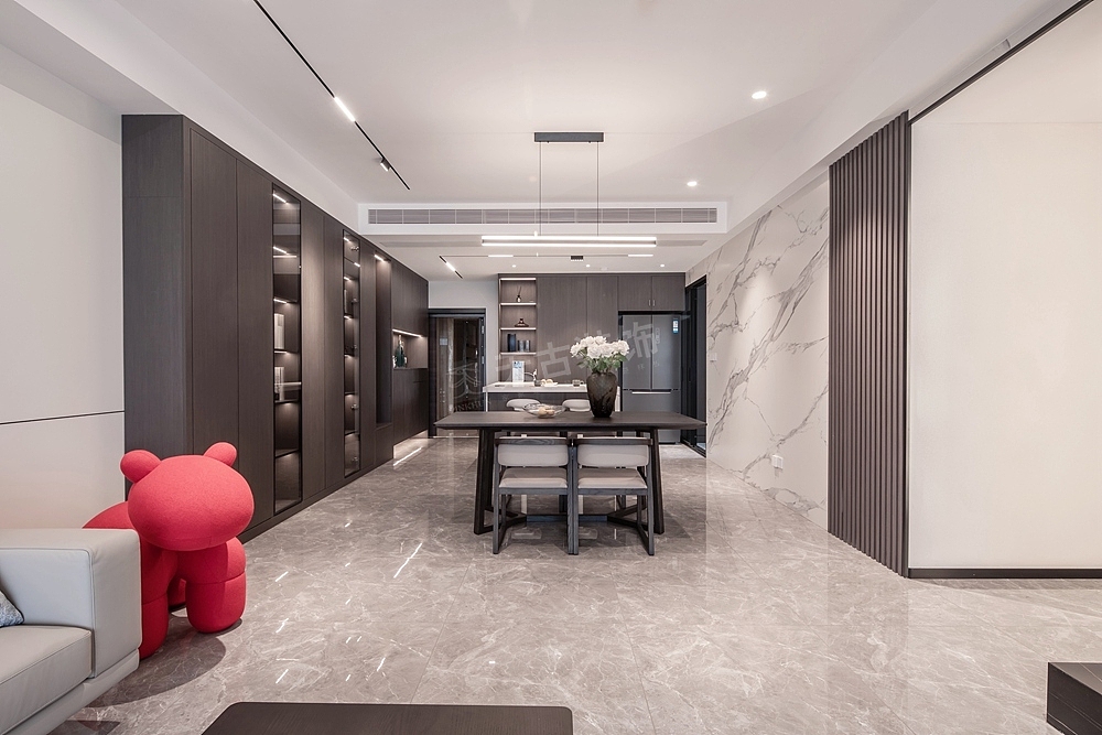 大理石背景墙的沉稳,与黑色茶几的质感,流露出轻奢的低调气质。沙发后面的护墙板简洁大气,与木饰面拉槽相结合,穿插着线性灯带的光源。沙发旁的红色小马,使得空间色彩更加丰富,带来节奏上层次的变化。