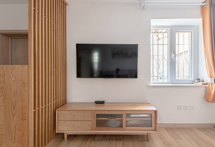 电视背景墙区域1500mm长的原木色电视柜与木木格栅相呼应，傍边的窗台上预留了空间，后期可以养绿植来点缀。窗台下方预留插座电源，后期屋主要加空气净化器，加湿器都可以在这里安排。
