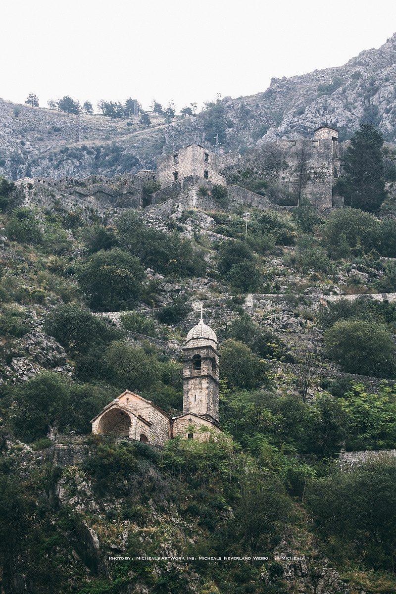 从古城街区的位置看向城墙的部分，大概有一个概念了，最上方的部分就是圣乔凡尼城堡的部分，中间的山间小教堂周围遍布着许多野猫~但是教堂本身我去的时候并没有开~可以看到最高的部分城堡墙面高度还是很高的，很是宏伟，不过年代久远整个外围斑驳的样子和山体融合在一起，反而隐藏效果极佳呢- -~如果现在当做防御城墙，效果或许更好hhhh~以上，这里就是黑山共和国的科托尔，一座隐藏于山野之间的古代堡垒，接下来，是惊艳城，与它完全不同风格的妖艳城池。
