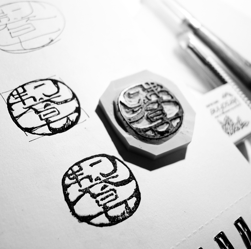 给橡皮章拍匀印泥,盖在本子上,用相机拍摄后扫描到PS中,再经过AI的调试,