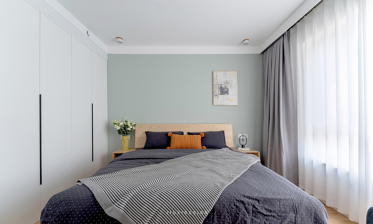 主卧以豆蔻青和白色为背景色,浅色调的原木床和床头柜,让卧室空间更接近自然,舒适具有温度。
床品的深灰色和窗帘浅灰,形成空间的明度架构,静谧安逸中有了层次变化。<br>