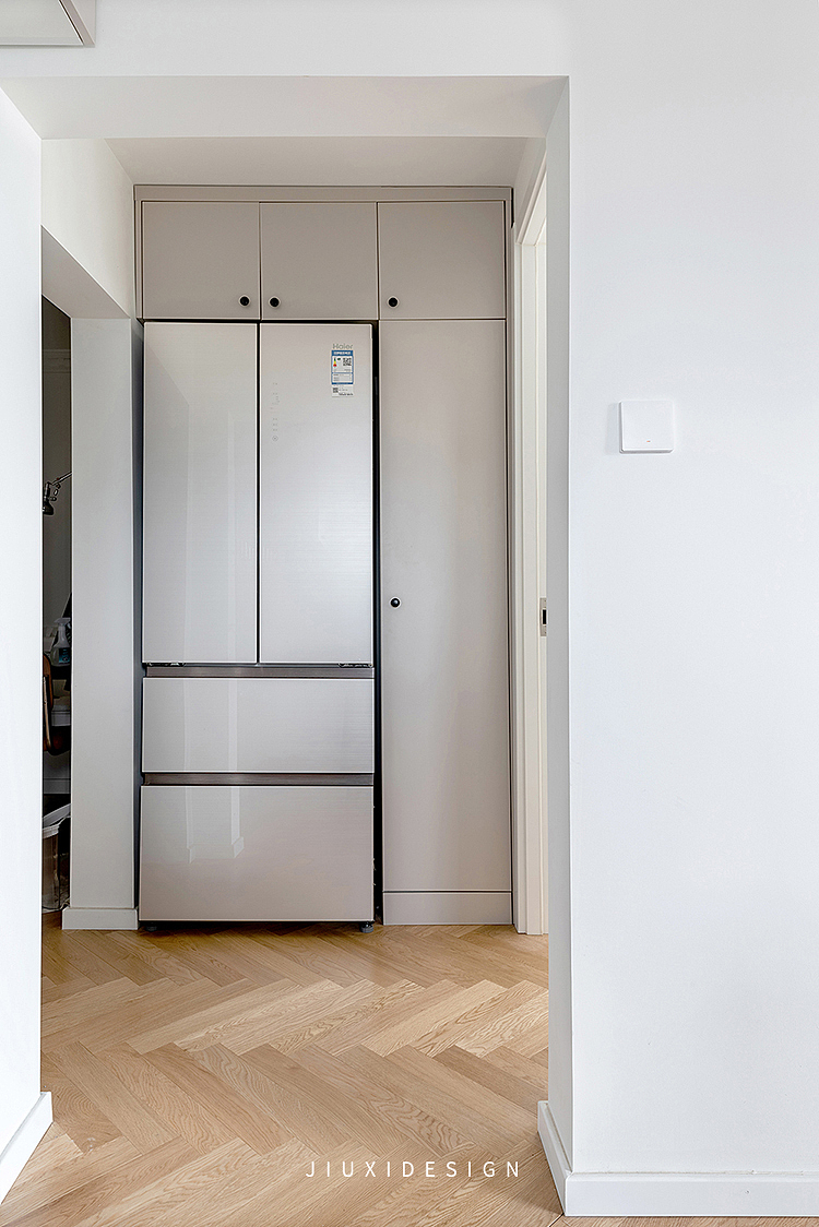 将原来主卧的隔墙，向内位移后，正好可以增加一组能容纳内嵌冰箱的收纳柜。且更改完毕后，冰箱位于整个空间的中心位置，方便各个空间拿取物品。
