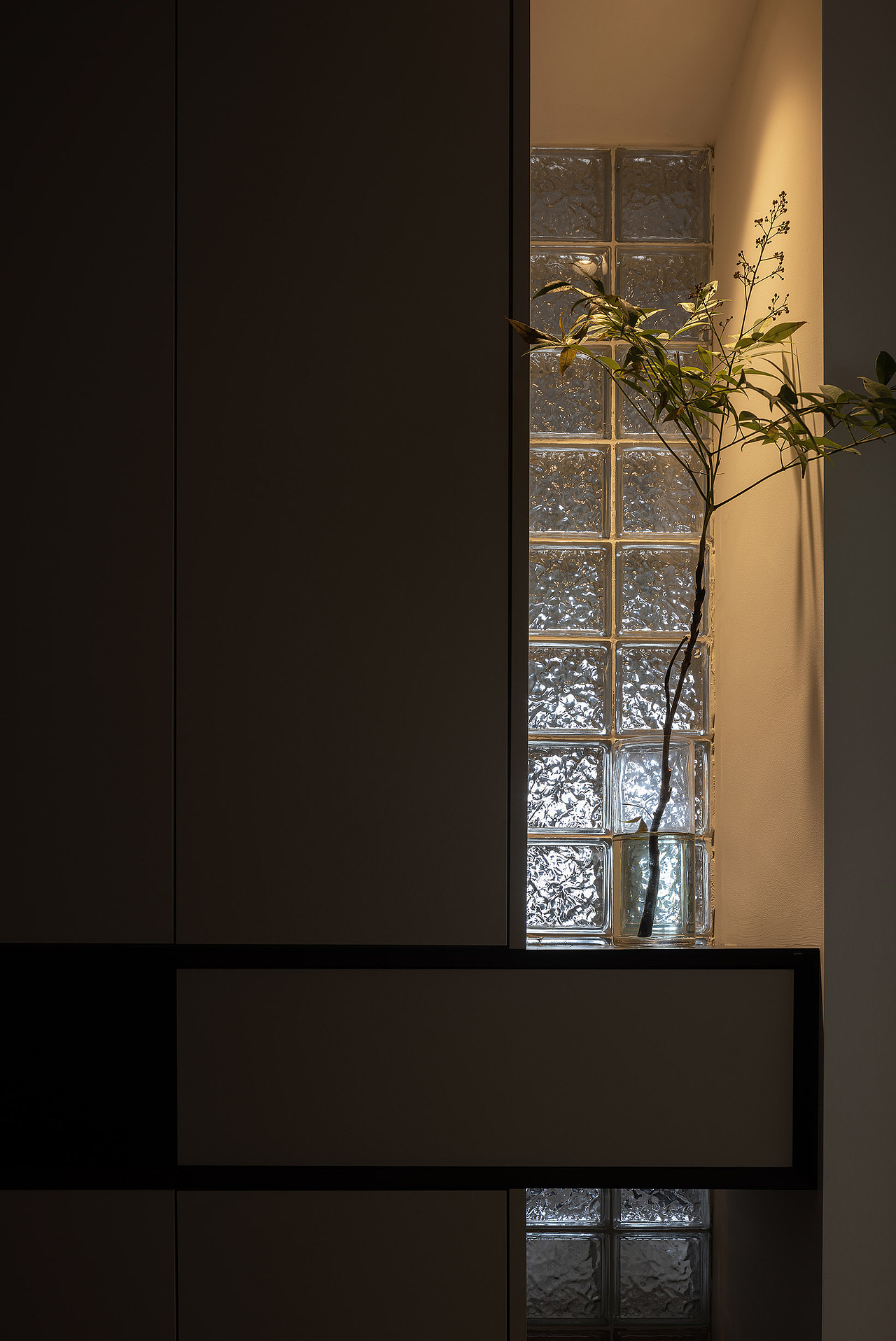 依循结构延展出收纳柜体，采用居中穿插手法，引入块面，融合凹嵌造型，包裹温馨暖光，搭配晶莹剔透的玻璃砖墙，映衬出新的诗境，向地面投射朦胧恬淡的光影，欢迎归家的人。