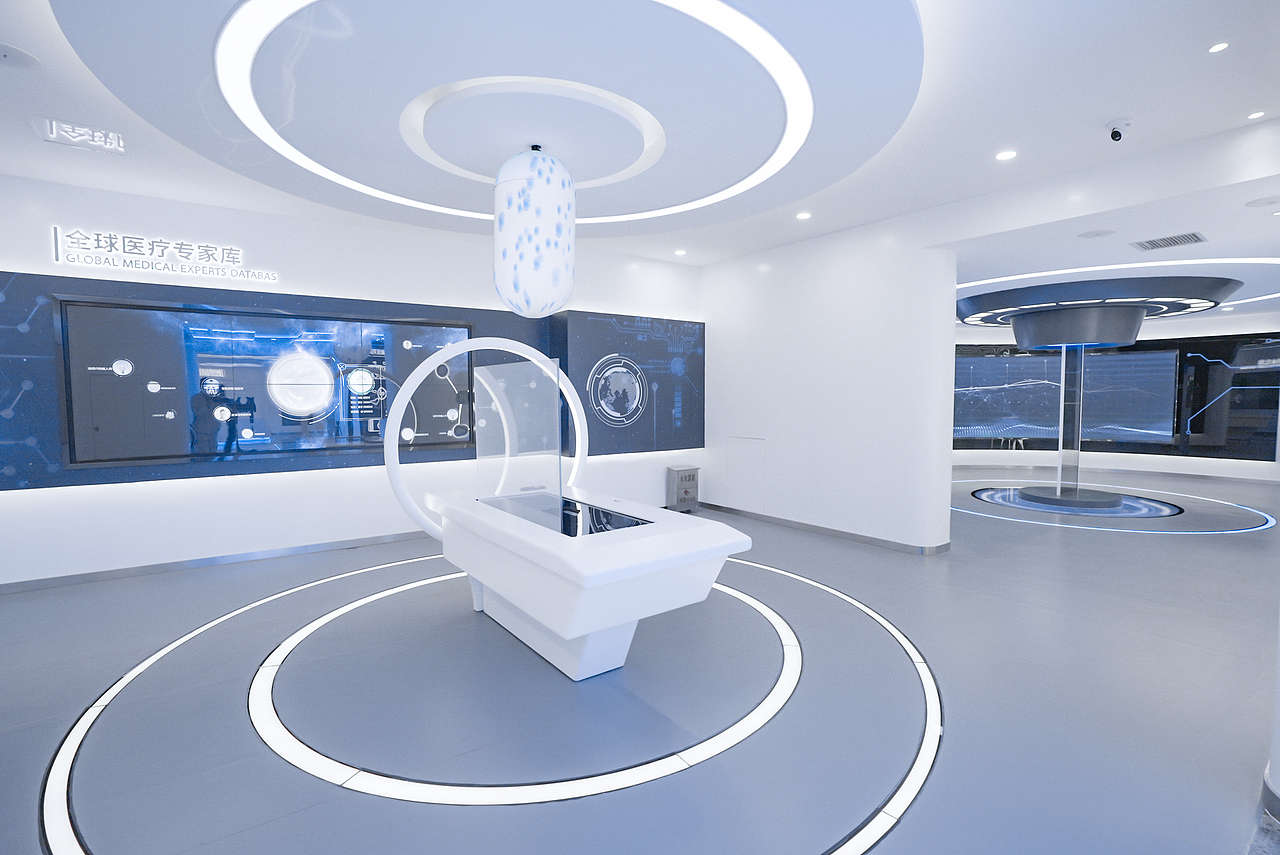 “生命之光”治疗空间,AI医生将为患者定制专属“生命之芯”智能胶囊,通过裸眼3D无介质空气成像技术,观众选择不同病症对应的治疗胶囊并查看相关信息,台面中央LED胶囊装置随之变换颜色和特效。前方屏幕则会同步演绎蕴含治疗芯片的胶囊进入人体进行治疗的过程。另一侧墙面则设置了触控交互屏,观众可自主点选查看全球医疗专家库相关信息。