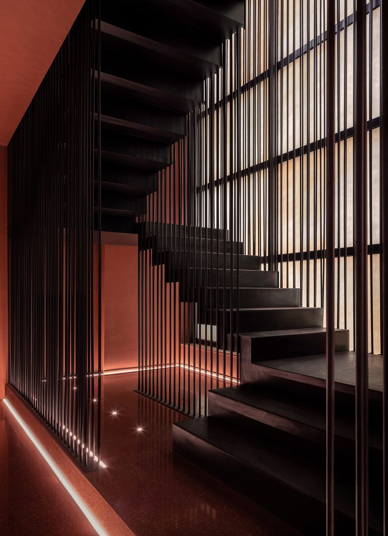 通过增加楼板、控制尺度,原始场地“生长”为一个附带挑空区域的双层空间。一层尽头处设置了楼梯厅,作为两层之间的竖向通道。楼梯厅采用几乎与原空间等高的金属圆管,通过紧密的排列,组成一道有序的“屏风”,不仅保证了通行时的安全性,也丰富了访客上行下至的交通体验。在这道“屏风”的庇护下,访客完成了从一层到达二层时的情绪转换,即由一处安静内敛的空间,逐步走向豁然开朗的区域,感受充裕的自然光与开阔的视野。