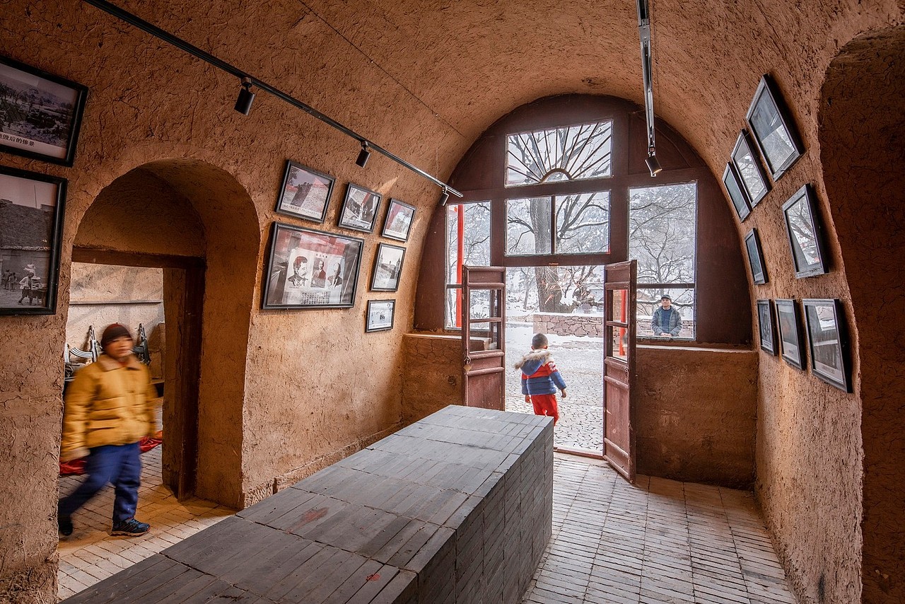 本项目是韩洪沟老村整体复兴计划一部分,基地是一个三合院,位于韩洪沟老村中部,地势较高。院落中有一个处空置的三孔窑洞,现状保持较好,但厢房、倒座、围墙和院门已经坍塌,只剩下基础的石块。场地中最为重要的元素是院外的大槐树。它已经有数百年的树龄,但仍然枝繁叶茂,如同神灵般守护着村庄。听村里老人介绍,大槐树下一直是村民集会的地方,以前是韩洪沟老村重要的公共空间,也是村庄的精神之地。