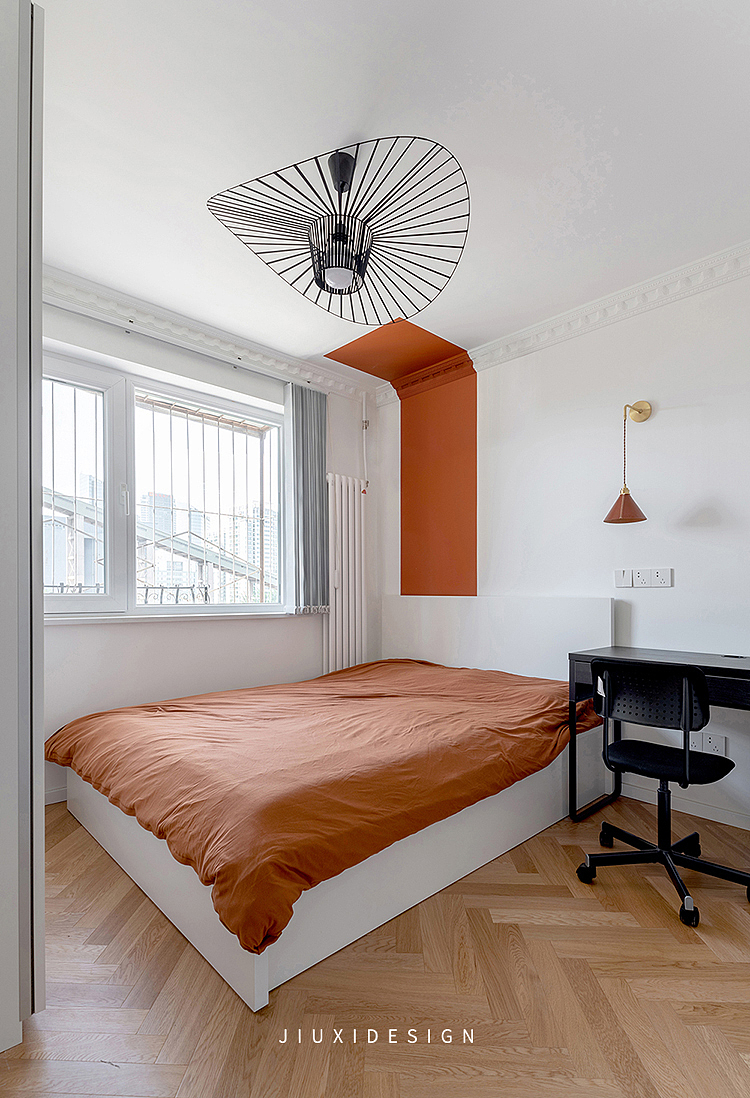 从色彩着手，给次卧做了色块上的区分。墙上条状的橘红色给整个空间带来活跃的氛围，自带延续感的人字拼地板，让小卧室显大。
