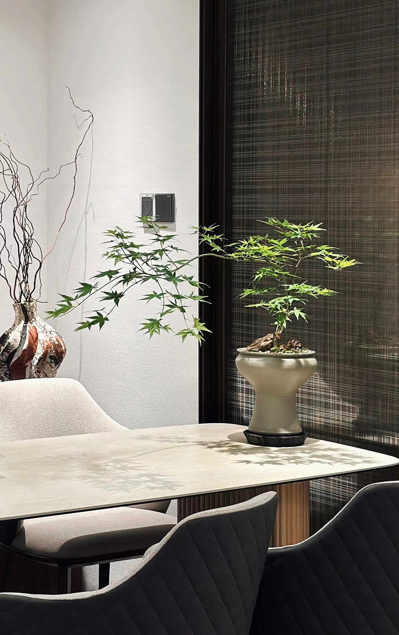 客厅沙发右侧是厨房门与就餐区,放置大理石餐桌与皮革餐椅,后方添置木墩子与造型独特的植物搭配。