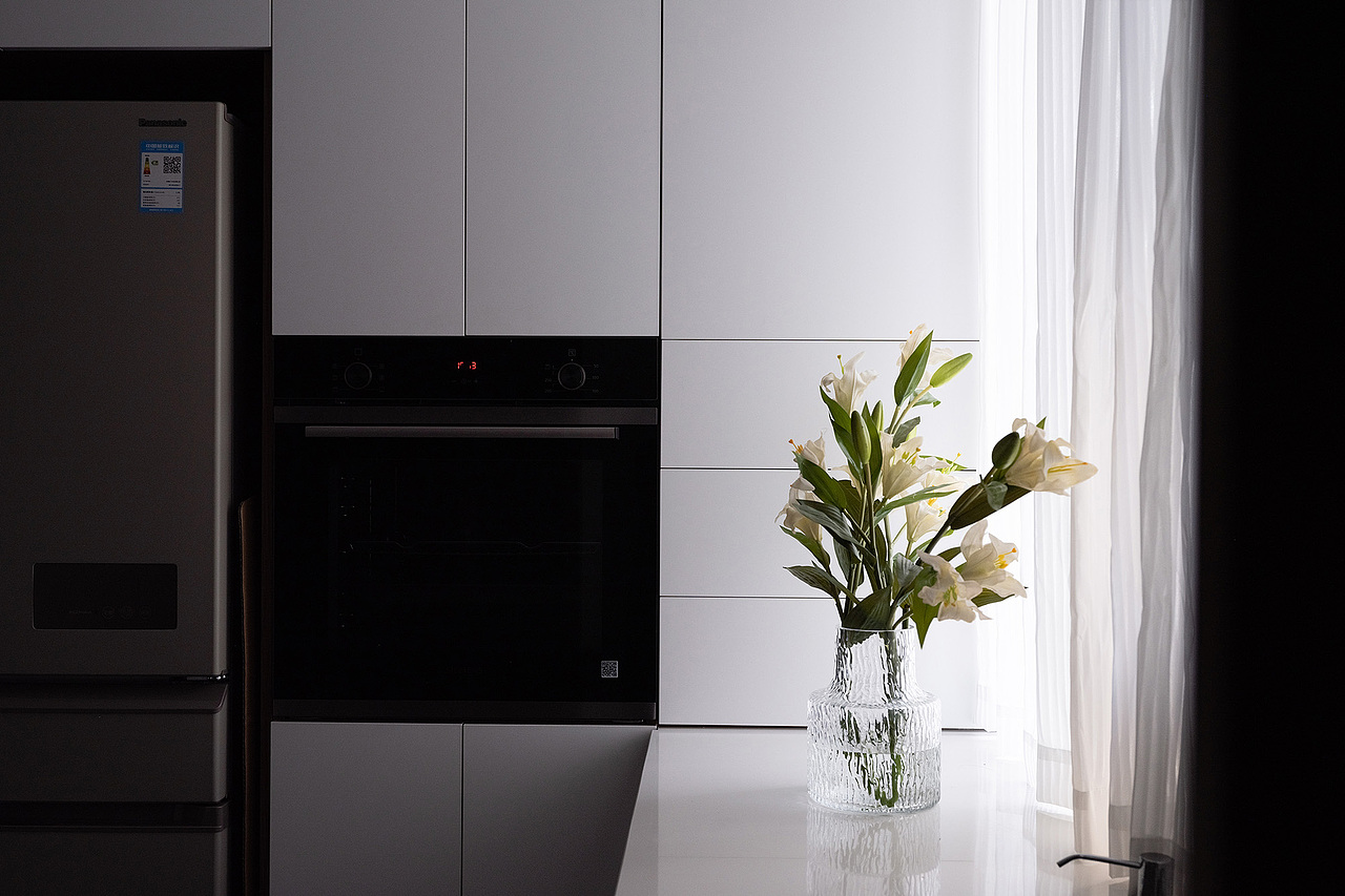 原始的厨房空间大小有限,无法满足更舒适性的使用诉求。结合可以外拓的露台,我们将原始的北面露台空间延展至室内,演变成西厨空间,与餐厅保持连通与关联。打造融合入户、门厅、西厨、吧台的一体式空间,既从空间结构上重塑了敞阔感,又从功能上丰富了实用性。