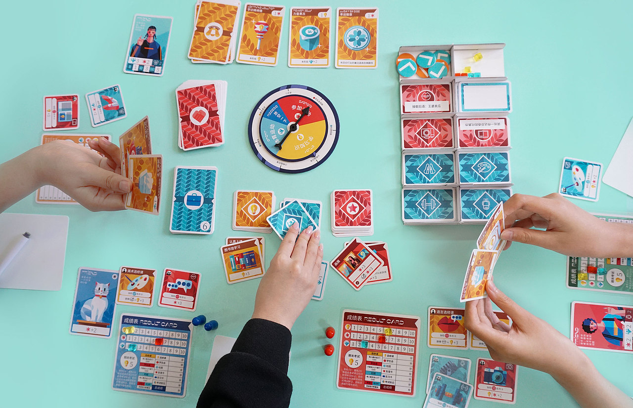 在《麻吉新生》这款桌游中玩家扮演“麻吉学院”的新生,在游戏中体验奇妙的大学校园生活。
大学背景的设定是为了营造一个熟悉的背景,让玩家能更快的带入游戏角色,激发玩家游戏过程中的更多情感共鸣与游戏过后的交流。在游戏中借鉴了大量的破冰团建游戏,希望玩家通过游戏能够快速打破人际壁垒,营造活跃的交友环境。