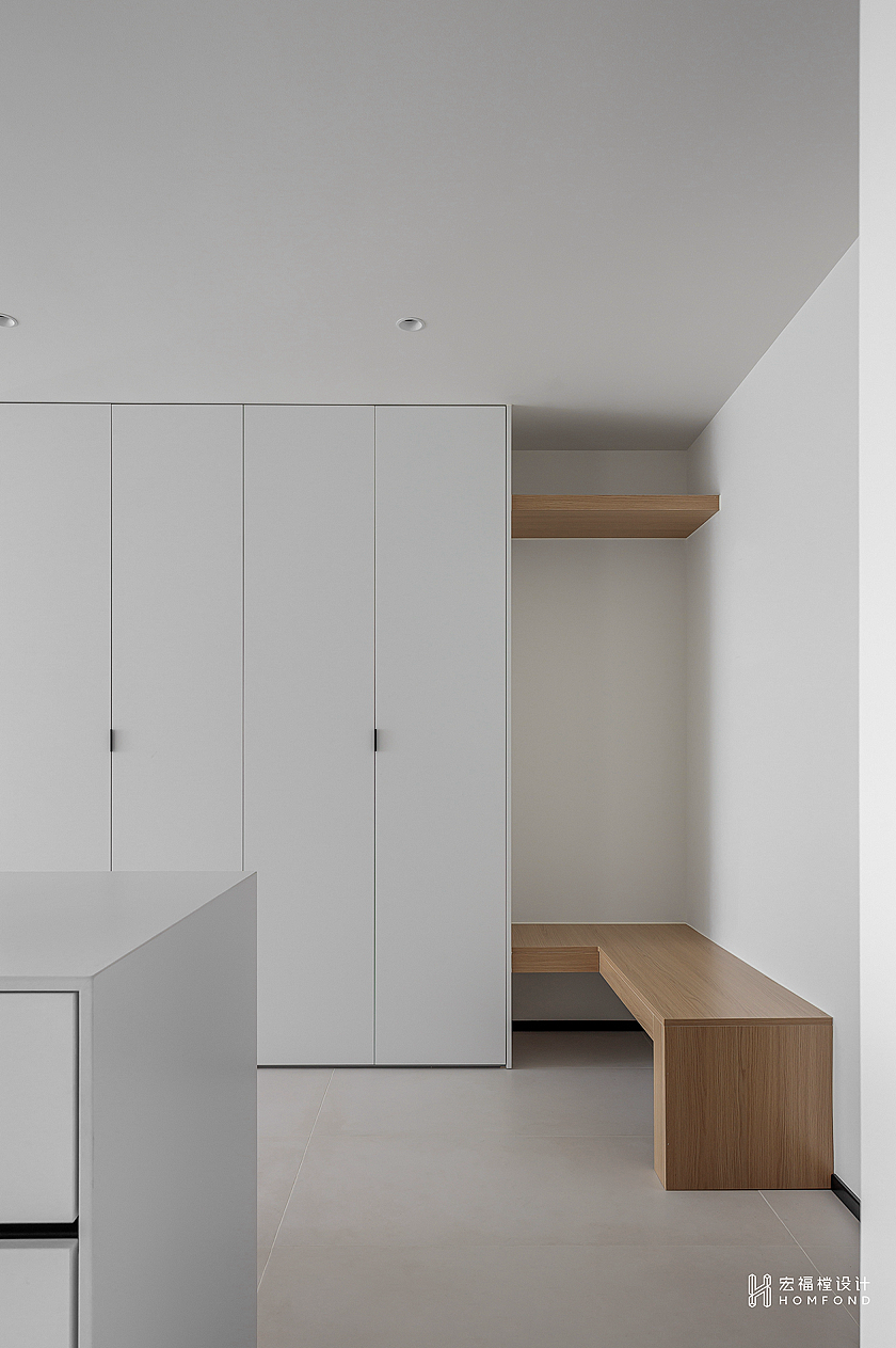 平衡空间之间的关系，从而达成清晰透彻的组合结构。拆除厨房墙体后，入户得到了最大视觉的开放。整面与墙体融合的纯白储物柜（大容量可放置四季鞋履、日常杂物），并定制原木条凳（方便入户换鞋），延续柜体与墙面之间的关系，也与客厅地板材质产生呼应。