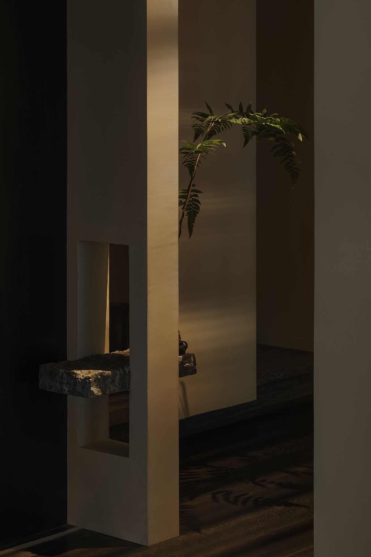 半墙下部又开出小窗,一块黑色花岗岩大理石悬浮穿过其中,石材上开凿的肌理纹路被保留,仅仅只是上面放上盆栽,就好似立刻有了山林之壁的意象蔓延开来。